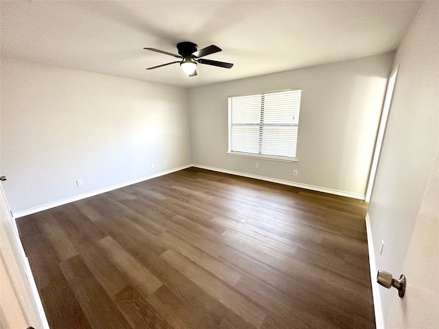 empty room featuring baseboards, dark wood finished floors, and a ceiling fan