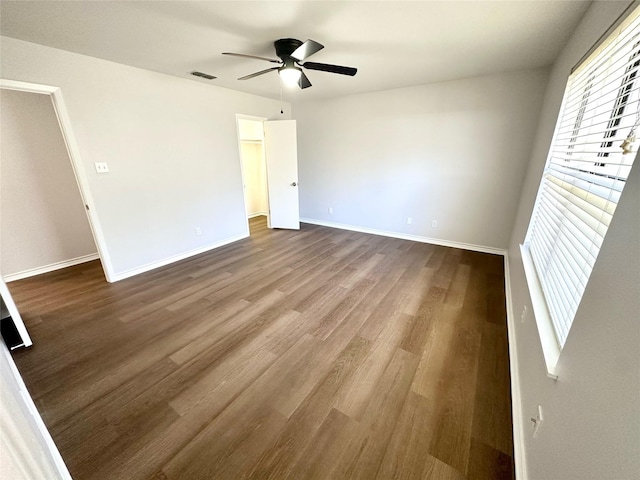 unfurnished room featuring visible vents, wood finished floors, a ceiling fan, and baseboards