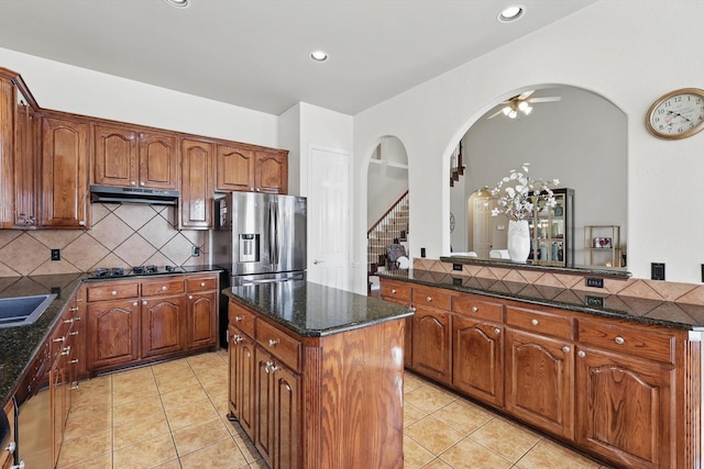 kitchen with a kitchen island, under cabinet range hood, decorative backsplash, and light tile patterned floors