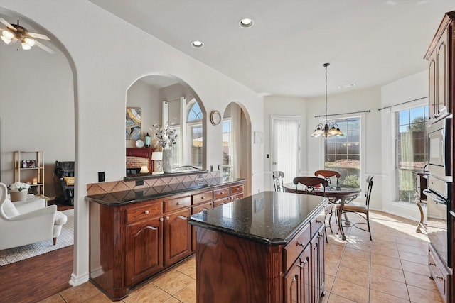 kitchen with a center island, pendant lighting, light tile patterned floors, recessed lighting, and black oven