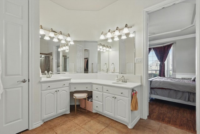 ensuite bathroom featuring double vanity, connected bathroom, a sink, and tile patterned floors