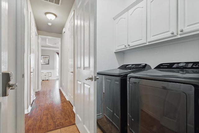 laundry room with washer and clothes dryer, wood finished floors, cabinet space, and baseboards