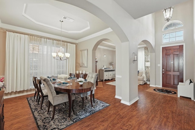 dining room with a chandelier, wood finished floors, visible vents, baseboards, and a tray ceiling