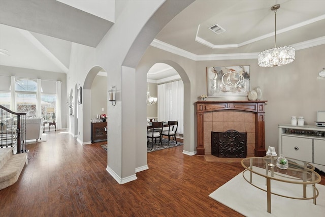 living room featuring baseboards, visible vents, a tiled fireplace, wood finished floors, and crown molding