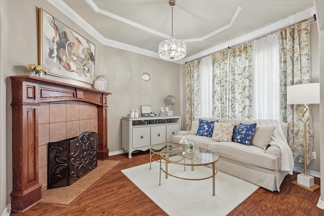 living area with ornamental molding, a tiled fireplace, wood finished floors, and baseboards