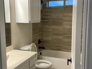 bathroom featuring toilet, tub / shower combination, and vanity