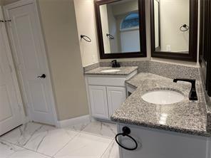 bathroom with marble finish floor, two vanities, a sink, and baseboards