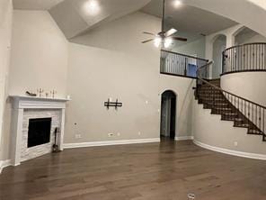 unfurnished living room featuring baseboards, ceiling fan, wood finished floors, stairs, and a fireplace