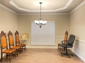 living area featuring a wainscoted wall, a tray ceiling, a decorative wall, and wood finished floors