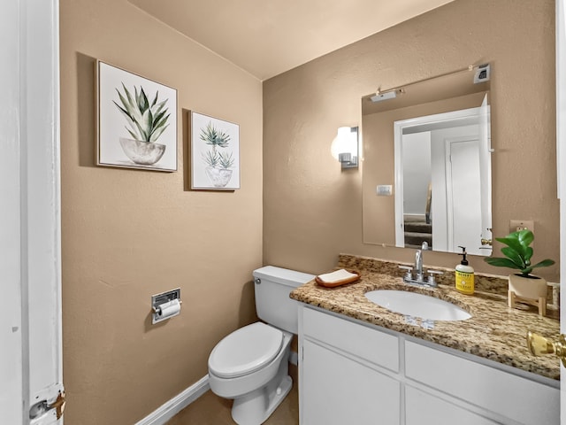 bathroom featuring toilet, baseboards, and vanity