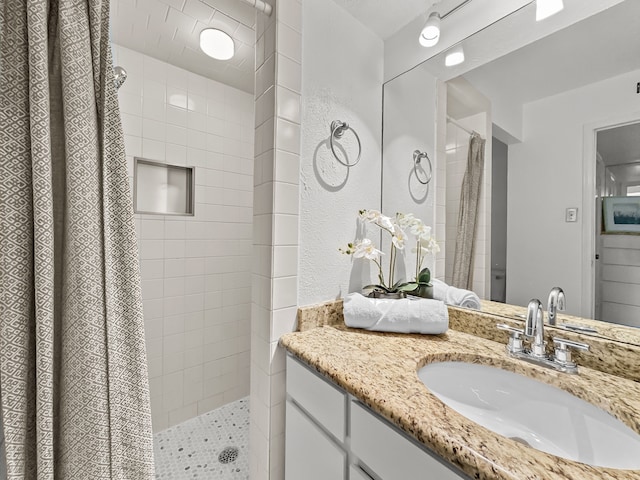 bathroom with tiled shower and vanity