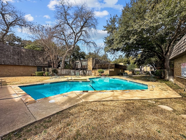 community pool with a patio area and fence