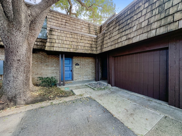 doorway to property featuring mansard roof and brick siding