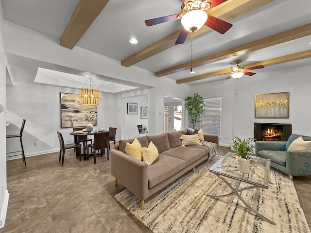 living area featuring a ceiling fan, a lit fireplace, baseboards, and beamed ceiling