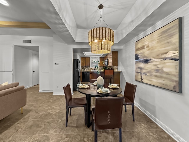 dining room with a tray ceiling, visible vents, baseboards, and an inviting chandelier