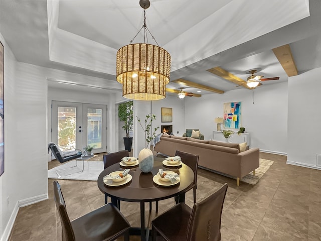 tiled dining space with baseboards, ceiling fan, beamed ceiling, a lit fireplace, and french doors