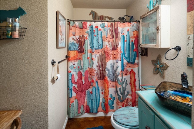 full bathroom featuring toilet, a textured wall, vanity, and a shower with shower curtain