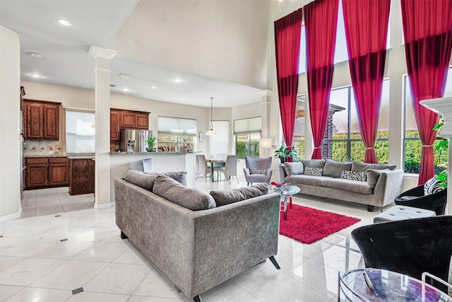 living area with a towering ceiling, light tile patterned floors, decorative columns, and recessed lighting