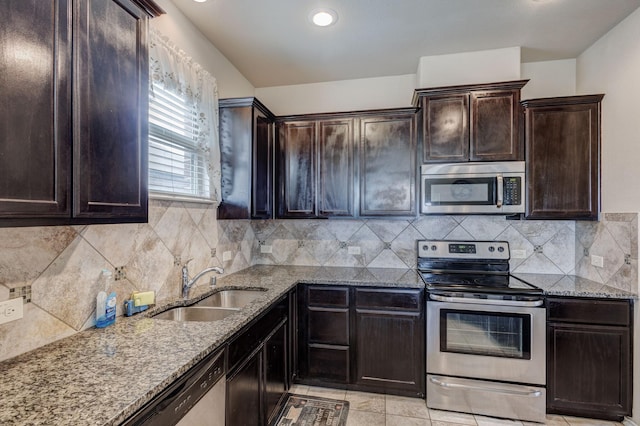 kitchen with a sink, decorative backsplash, light stone counters, and appliances with stainless steel finishes