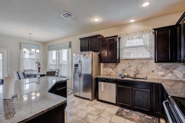 kitchen with visible vents, stone countertops, a sink, decorative backsplash, and appliances with stainless steel finishes