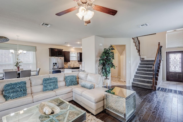 living area featuring visible vents, ceiling fan with notable chandelier, stairway, and wood finished floors