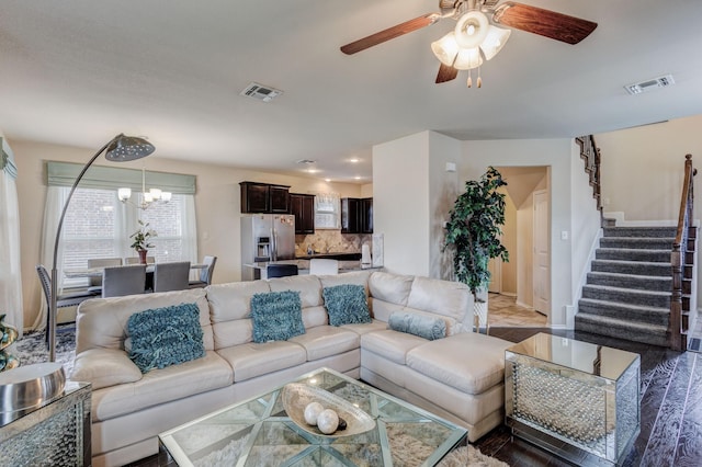 living area with visible vents, stairs, and ceiling fan with notable chandelier