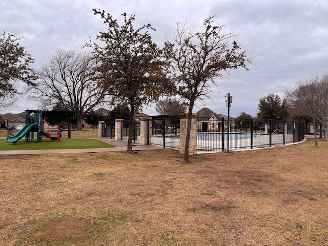 view of yard featuring a community pool, fence, and playground community