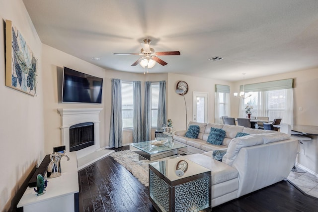 living area with dark wood finished floors, a fireplace with raised hearth, visible vents, and a wealth of natural light