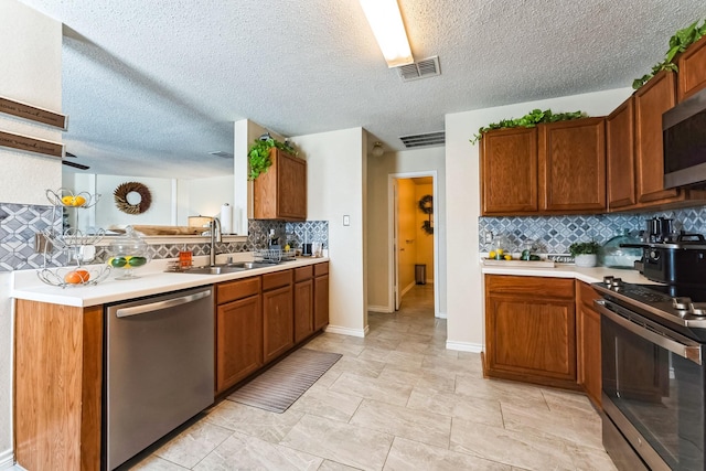 kitchen featuring a sink, visible vents, light countertops, appliances with stainless steel finishes, and brown cabinetry