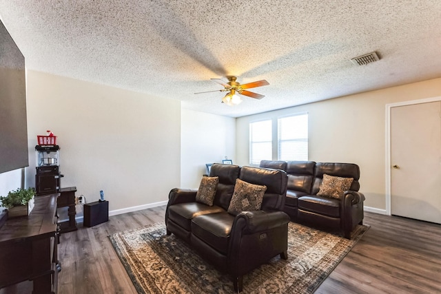 living area featuring a ceiling fan, visible vents, a textured ceiling, and wood finished floors