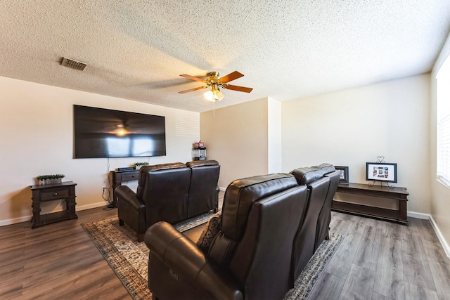 cinema room featuring visible vents, a ceiling fan, a textured ceiling, wood finished floors, and baseboards