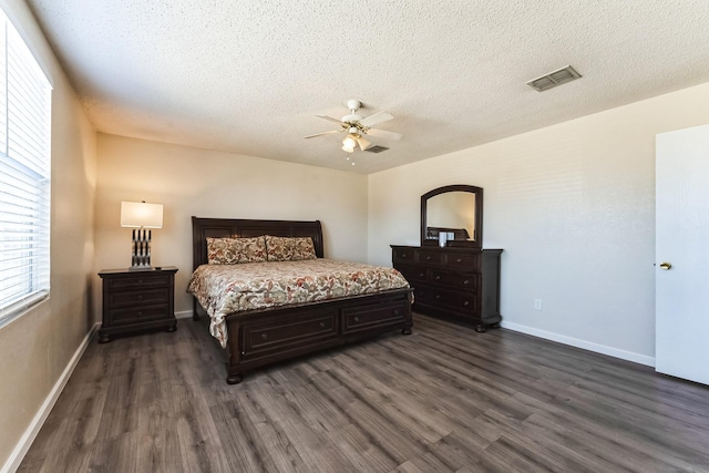 bedroom featuring dark wood-type flooring, visible vents, a textured ceiling, and baseboards