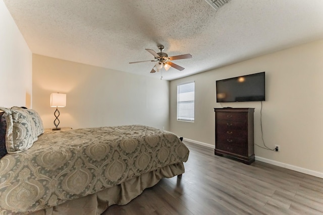 bedroom featuring baseboards, visible vents, ceiling fan, wood finished floors, and a textured ceiling