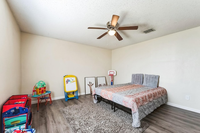 bedroom with baseboards, visible vents, ceiling fan, wood finished floors, and a textured ceiling