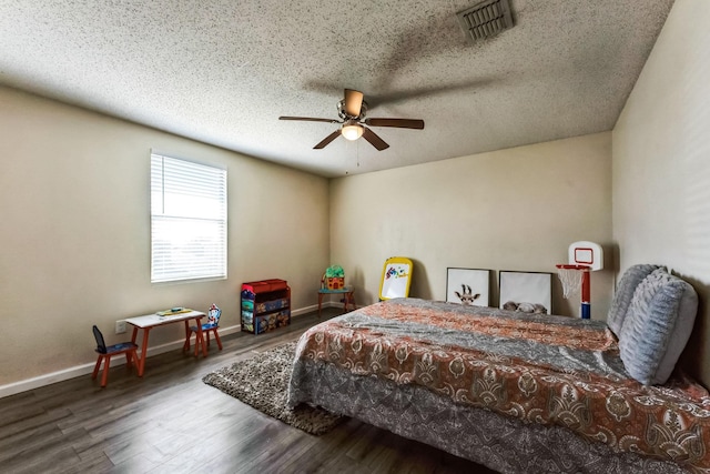 bedroom featuring a textured ceiling, wood finished floors, a ceiling fan, visible vents, and baseboards