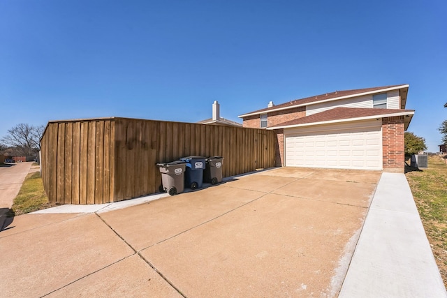 view of side of home featuring a garage, concrete driveway, brick siding, and cooling unit