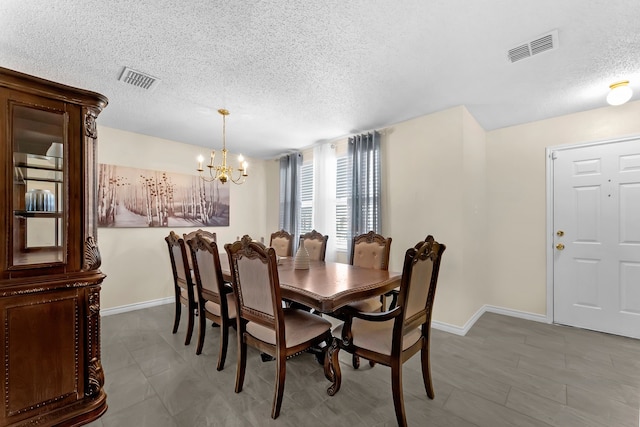 dining area featuring a textured ceiling, baseboards, visible vents, and an inviting chandelier