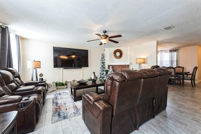 living area with light wood-style floors, visible vents, ceiling fan, and a textured ceiling