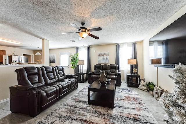 living area with a ceiling fan, visible vents, plenty of natural light, and a textured ceiling