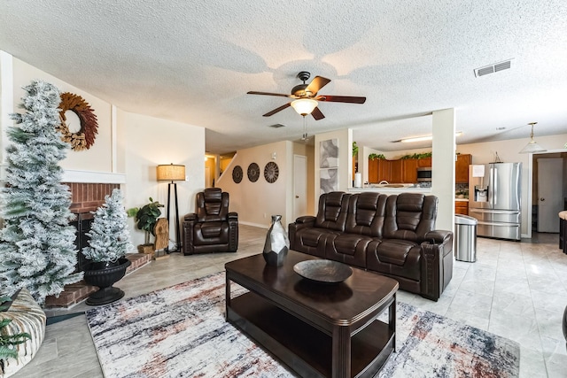 living room featuring a ceiling fan, visible vents, and a textured ceiling