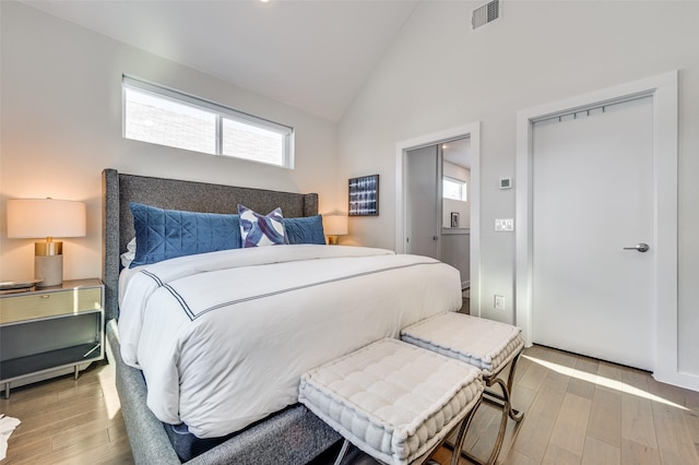 bedroom with lofted ceiling, visible vents, and wood finished floors