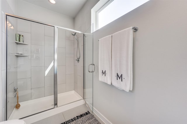 bathroom with a stall shower, tile patterned flooring, and baseboards