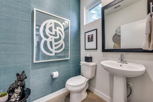 half bath with toilet, baseboards, visible vents, and a sink