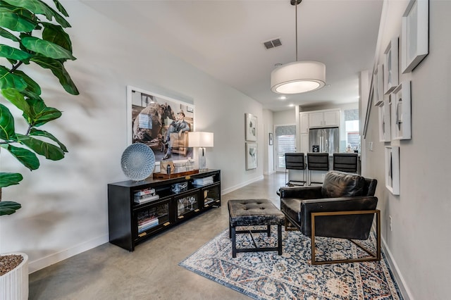 living room featuring concrete floors, visible vents, and baseboards