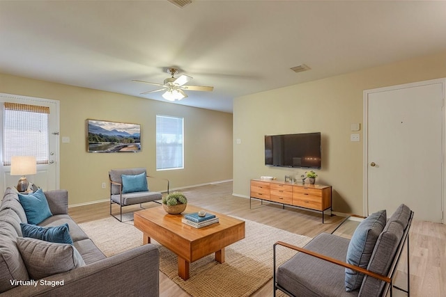 living area featuring light wood-style flooring, visible vents, ceiling fan, and baseboards