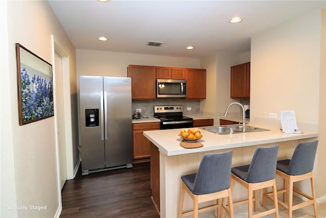 kitchen with a peninsula, stainless steel appliances, a sink, and a kitchen breakfast bar