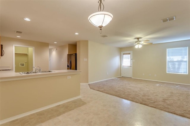 spare room with baseboards, a sink, visible vents, and light colored carpet