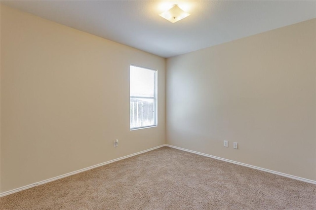 carpeted empty room featuring baseboards