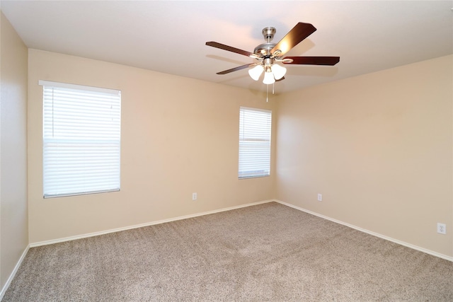 carpeted spare room with baseboards and a ceiling fan