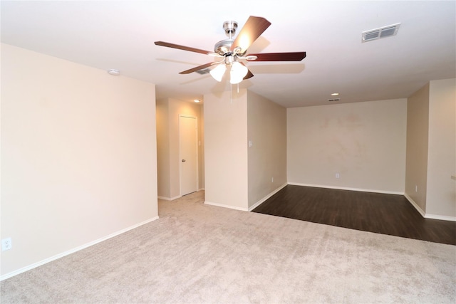 carpeted empty room with baseboards, visible vents, and a ceiling fan